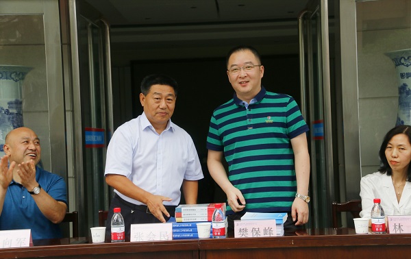 新乡市牧野区税务局党委书记、局长樊保峰向华体会(中国)党委书记张会民赠送税法知识书籍.jpg